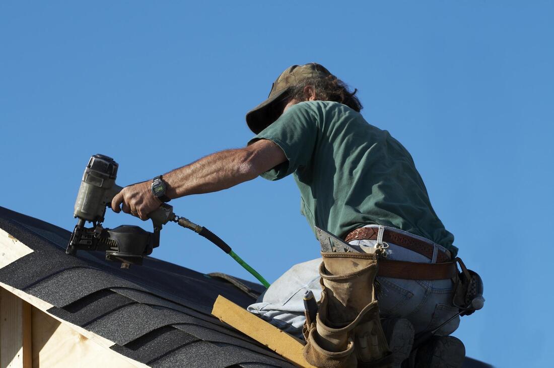 worker in the roof using a nailer